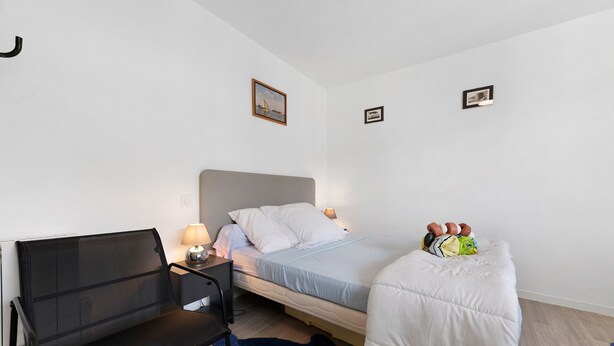 Ein Schlafzimmer mit einem Bett, einem Sessel, einem Schreibtisch und zwei Wandleuchten.