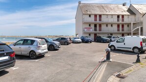 Ein Parkplatz mit mehreren Autos, ein Gebäude mit Balkonen und ein Schild, das privates Eigentum kennzeichnet.