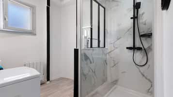 A modern bathroom with a glass-enclosed shower, a white toilet, and a window above the sink.