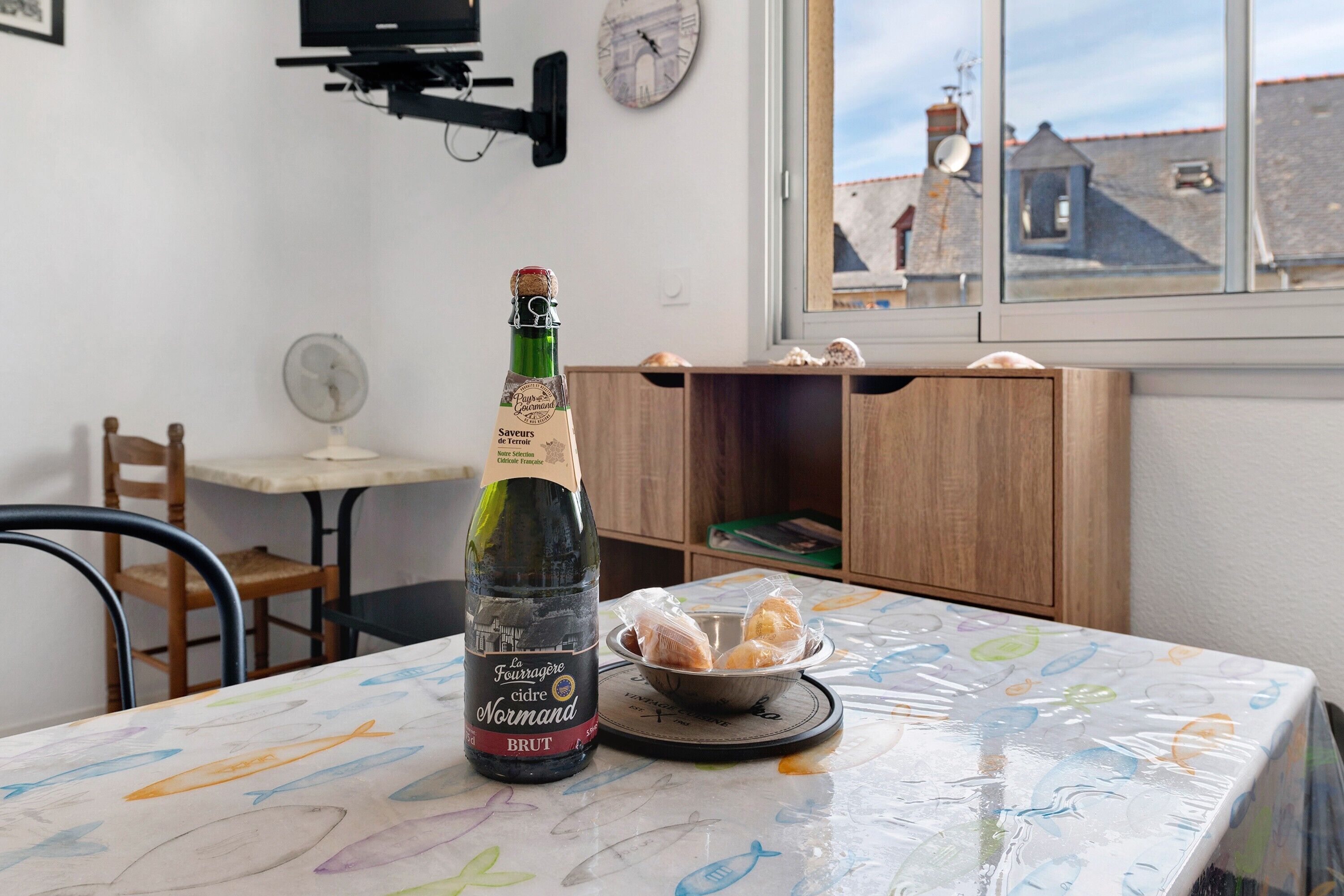A bottle of wine on a table with a view of buildings through a window.