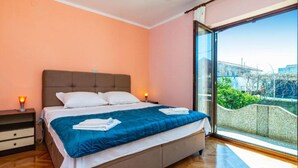 A bedroom with a bed, bedside tables, a nightstand, a large window with a view, and a ceiling fan. - Two Bedroom Apartment With Terrace (Preko)