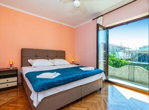 Ein Schlafzimmer mit einem Bett, Nachttischen, einem Schreibtisch, einem großen Fenster mit Blick und einem Deckenventilator.