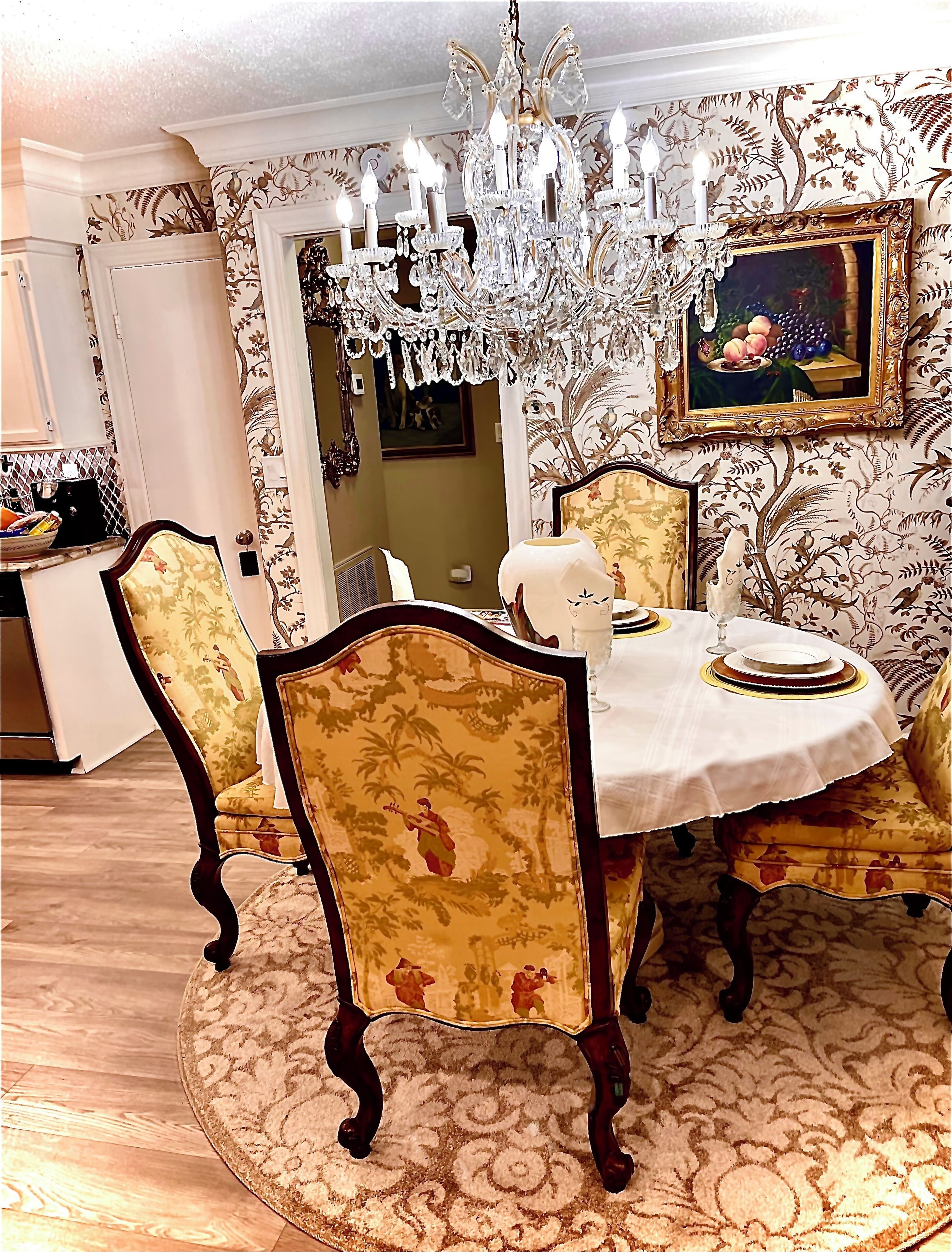 Un coin repas agrémenté d’un lustre, d’un papier peint à motifs floraux et d’une table ronde avec des chaises.