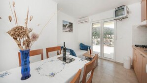A dining area with a table set for two, a blue vase with dried flowers, and a picture on the wall. - Bertie's Lodge - Two Bedroom Apartment With Terrace and Sea View (Smokvica)