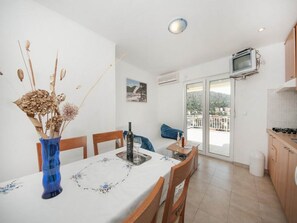 A dining area with a table set for two, a blue vase with dried flowers, and a picture on the wall. - Bertie's Lodge - Two Bedroom Apartment With Terrace and Sea View (Smokvica)