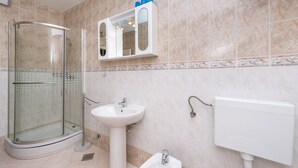Un bagno con box doccia in vetro, lavabo su piedistallo e water.