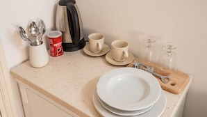 A kitchen counter with a coffee maker, cups, a glass carafe, and utensils. - Guest House Lumin - Twin Room With City View (Dubrovnik)