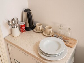 A kitchen counter with a coffee maker, cups, a glass carafe, and utensils. - Guest House Lumin - Twin Room With City View (Dubrovnik)