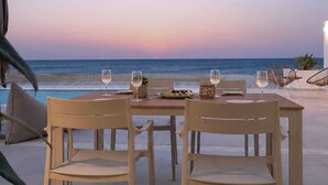Een eettafel met stoelen op een terras met uitzicht op de oceaan.