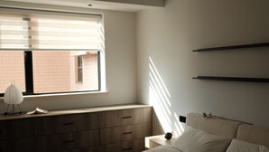 Una camera da letto con un letto, una cassettiera, un comodino e una finestra con persiane.