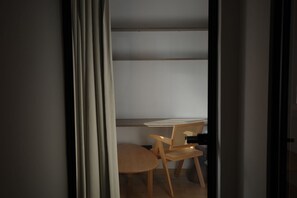 Ein Zimmer mit Schreibtisch, Stuhl und Bücherregal.