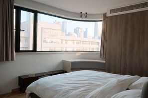 Ein Schlafzimmer mit großem Fenster, einem Bett, einem Nachttisch und einer eingebauten Sitzbank.