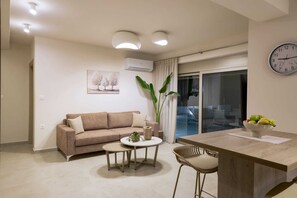 Ein modernes Wohnzimmer mit einer Couch, einem Couchtisch und einem Essbereich mit einem Stuhl und einer Obstschale.