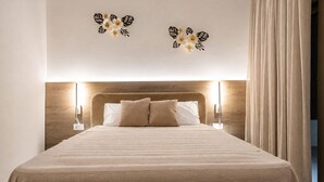 A hotel room with a large bed, two wall-mounted lamps, and a wooden headboard. - Azzurro Luxury Villa 2 (Rhodes)