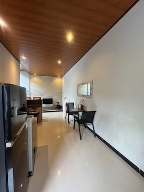 A modern kitchen with a refrigerator, sink, and a dining area with chairs and a table.