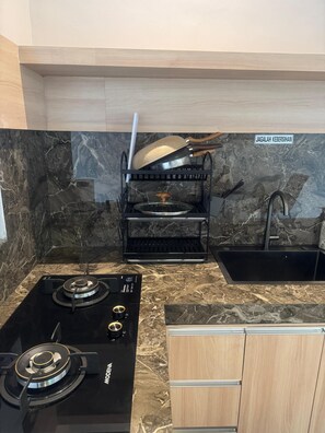 A kitchen with a black stove, a sink, and a wooden cabinet.