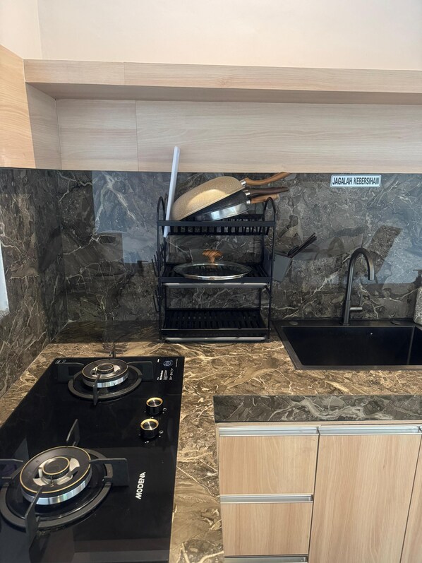 A kitchen with a black stove, a sink, and a wooden cabinet.