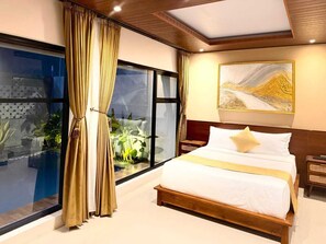 A bedroom with a large bed, a view of a pool, and a painting on the wall.