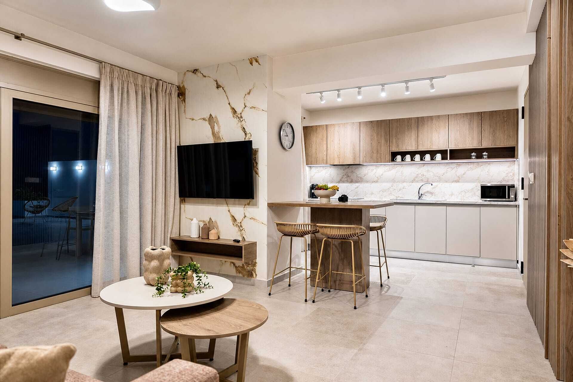 A modern kitchen with a dining area, a flat-screen TV, and a clock on the wall.