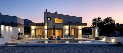Une maison moderne à deux étages, dotée d’une piscine, d’un espace extérieur aménagé et d’une entrée bien éclairée.
