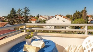 Un balcon avec une table, un livre et une plante en pot.