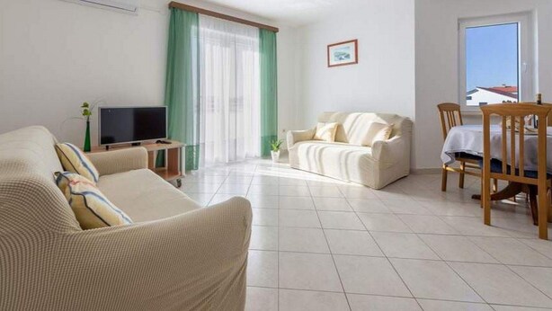 Un salon comprenant un canapé, un téléviseur, une table à manger avec des chaises et une fenêtre donnant sur un beau paysage.