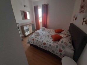 Ein Schlafzimmer mit einem Bett, einem Schminktisch, einem Spiegel und einem Fenster mit Vorhängen.