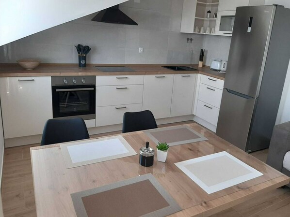 Eine moderne Küche mit weißen Schränken, einem Edelstahlkühlschrank und einem Esstisch mit Platzdeckchen.
