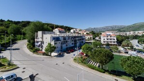 A multi-story building with a parking lot in front, surrounded by greenery and a clear sky. - Apartment Stella Polaris - Studio Apartment A2 (Dubrovnik)