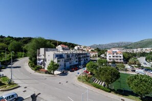 A multi-story building with a parking lot in front, surrounded by greenery and a clear sky. - Apartment Stella Polaris - Studio Apartment A2 (Dubrovnik)