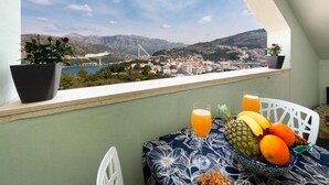 A balcony with a table set for breakfast, a view of a bridge, and a cityscape. - Apartments Meri & Karla - Two Bedroom Apartment With Balcony and Sea View (Dubrovnik)