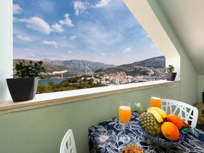 Ein Balkon mit Frühstückstisch, Blick auf eine Brücke und eine Stadtlandschaft.