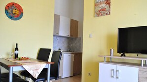 A compact kitchen with a dining area, a television, and a wall decoration. - Apartments Smokvica - Superior One Bed /apt (Starigrad)