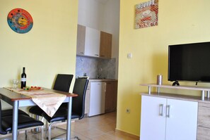 A compact kitchen with a dining area, a television, and a wall decoration. - Apartments Smokvica - Superior One Bed /apt (Starigrad)