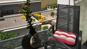 A balcony with a view of the sea, a chair with a red and white cushion, and a vase with yellow flowers. - Apartments Smokvica - Superior One Bed /apt (Starigrad)