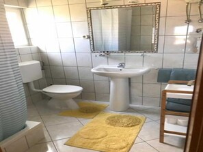 A bathroom with a toilet, sink, mirror, and a shower area. - Apartments Paloc - One-bedroom Apartment With Balcony (Bol)