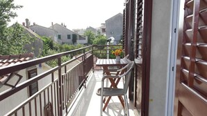 A balcony with a table and chairs, a potted plant, and a view of the surrounding buildings. - Apartments Paloc - One-bedroom Apartment With Balcony (Bol)