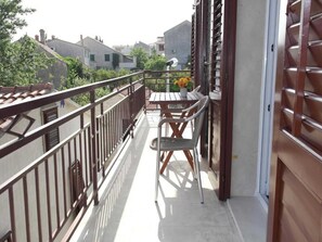 A balcony with a table and chairs, a potted plant, and a view of the surrounding buildings. - Apartments Paloc - One-bedroom Apartment With Balcony (Bol)