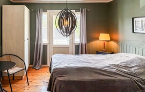 A bedroom with a bed, a chair, a table, a lamp, and a view of the outdoors through a door. - 4 bedroom awesome home in Byglandsfjord (Byglandsfjord)
