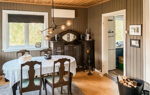 A dining area with a table set for four, a wooden cabinet with a mirror, and a window with blinds. - 4 bedroom awesome home in Byglandsfjord (Byglandsfjord)