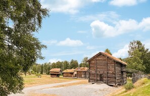 A rustic wooden cabin with a stone foundation, surrounded by a gravel path and lush greenery. - 4 bedroom awesome home in Byglandsfjord (Byglandsfjord)