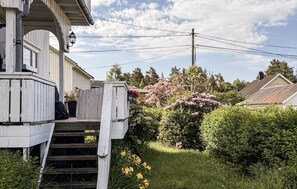 A wooden house with a porch, a staircase leading to the entrance, and a garden with various plants and flowers. - 4 bedroom awesome home in Byglandsfjord (Byglandsfjord)