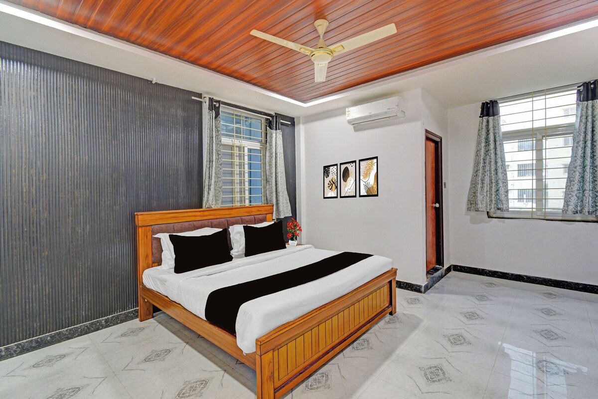 A bedroom with a wooden bed, a ceiling fan, a window with curtains, and a door.