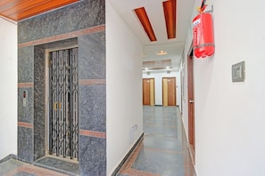 A hallway with a marble floor, a metal gate, and a red fire extinguisher. - Super Collection O Gachibowli Phase 2 (Hyderabad)