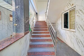 A staircase with a metal railing, marble walls, and a window with a floral pattern. - Super Collection O Gachibowli Phase 2 (Hyderabad)