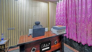 Una mesa de recepción con una computadora, una impresora y una botella de agua.