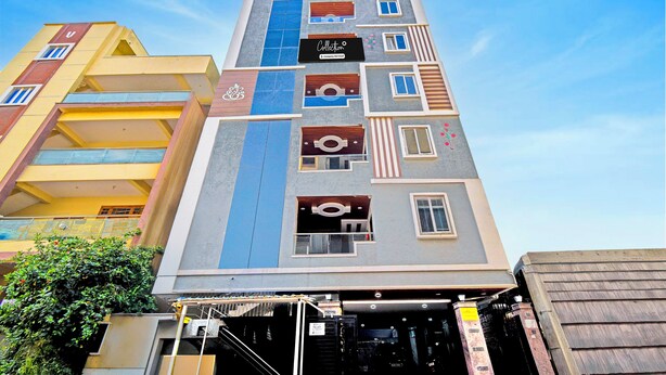 Un edificio de varios pisos con un diseño arquitectónico moderno, que presenta una variedad de formas y tamaños de ventanas, y un logotipo destacado en la fachada.