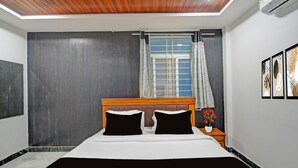 Un dormitorio con cama, mesita de noche, ventana con cortinas y aire acondicionado de pared.