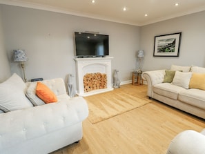 A living room with a fireplace, a television mounted above it, and two sofas with cushions. - 1 The Old Smithy (Cemaes Bay)