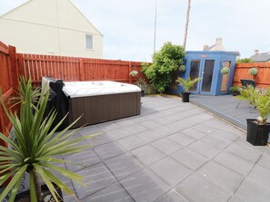 Un patio trasero con un jacuzzi, una valla de madera y plantas en macetas.